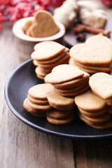 Heart shaped biscuits on plate with ash berry on wooden background