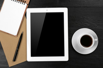 Digital tablet with cup of coffee and notebook on wooden table, closeup