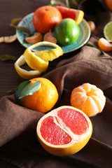 Fresh citrus fruits with green leaves on wooden table closeup