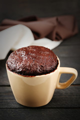 Chocolate fondant cake in cup on wooden table closeup
