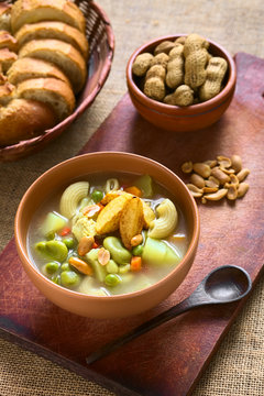 Traditional Bolivian Sopa de Mani (peanut soup) made of meat, pasta, vegetables (pea, carrot, potato, broad bean, pepper, corn) and ground peanut, photographed with natural light (Selective Focus)