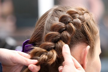 Fototapeta premium Professional hairdresser braiding clients hair