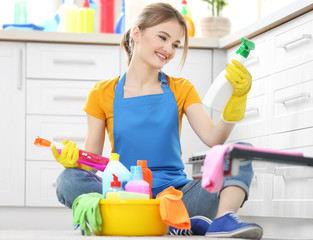 Cleaning concept. Young woman sitting on the floor with cleaning fluids