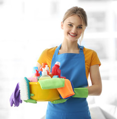 Cleaning concept. Young woman holds plastic basin with washing fluids and rags in hands
