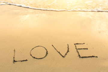 Love - written on sandy beach with the soft wave. .