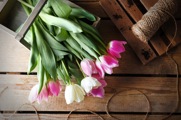 Bouquet of pink and white tulips with rope on wooden background
