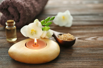 Spa set with sea salt, flowers and candles on wooden background