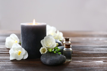 Spa composition with candle, pebbles and aroma oil on wooden background