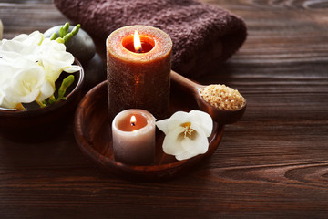 Fototapeta na wymiar Spa composition with alight candles and beautiful flowers on wooden background