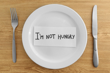 White plate with words I'm not hungry on wooden background