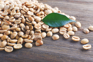Green coffee beans with a leaf on  wooden table