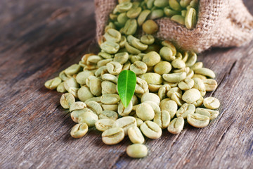 Green coffee beans with a leaf on  wooden table