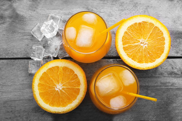 Glasses of orange juice with ice on rustic wooden background