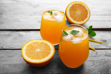 Glasses of orange juice with ice on rustic wooden background