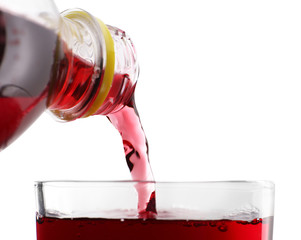 Pouring cherry soda from plastic bottle into glass on grey background