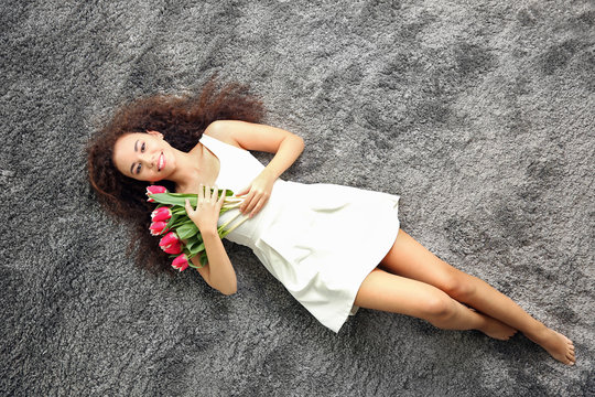 Young woman with tulips lying on the floor