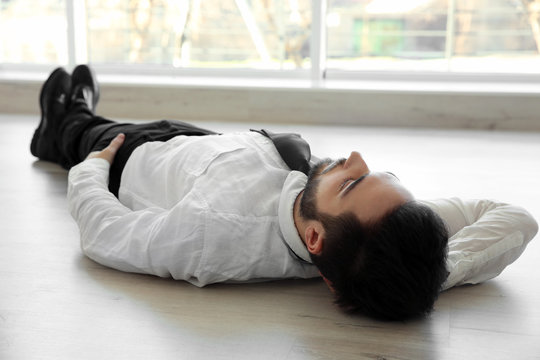 Young handsome businessman lying on the floor