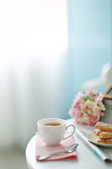 Cup of coffee with cookies on white table in light interior