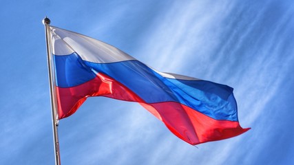 Flag of Russia. Russian Flag on Flagpole Waving in front of Blue Sky.