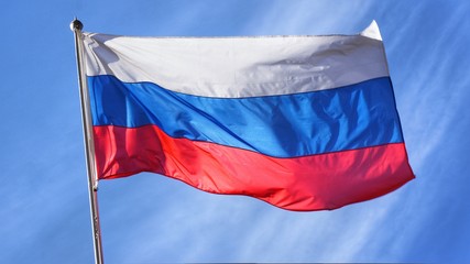 Flag of Russia. Russian Flag on Flagpole Waving in front of Blue Sky.