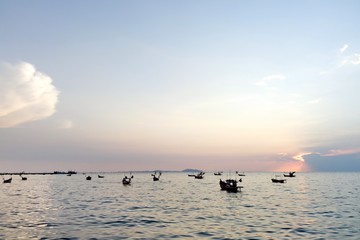 Fishing boats in sea on sunset