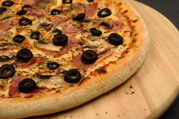 Pizza with ham, mushrooms, cheese and olives - isolated on black
