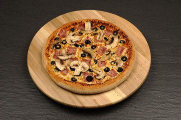 Pizza with ham, mushrooms, cheese and olives - isolated on black
