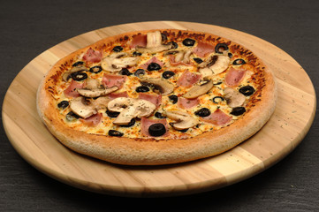 Pizza with ham, mushrooms, cheese and olives - isolated on black
