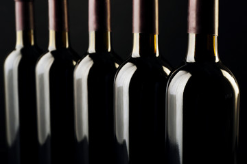 Wine bottles in a row on black  background, close up