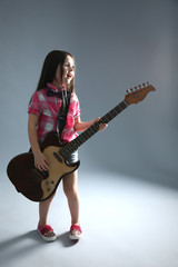 Fototapeta premium Beautiful artistic little girl playing guitar on grey background