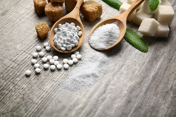 Pile of brown sugar cubes and stevia  on grey wooden background - obrazy, fototapety, plakaty