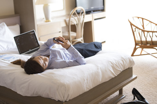 Women are looking at the smartphone lying on his back in the business hotel bed