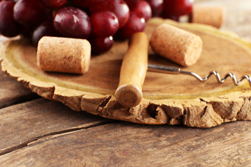 Wine corks and tailspin with bunch of grapes on wooden background