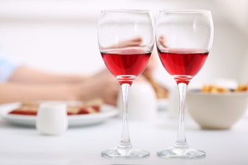 Dinner with glasses of wine on light blurred background