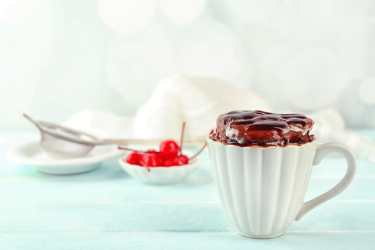 Chocolate mug cake with cream and cherry on a table