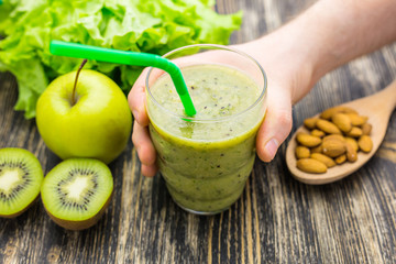 Healthy green smoothie with kiwi, apple on rustic wood background.