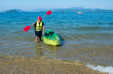 man carrying kayak paddle on shoulder at sea beach
