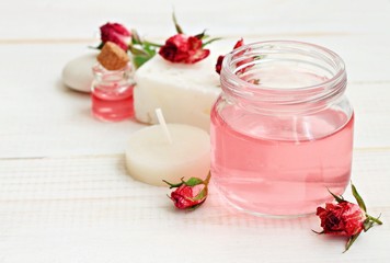 Rose water in jar, dried roses, candle, relaxing aromatherapy. Soft focus, soft light.