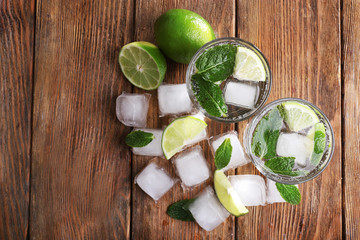 Fresh cocktails with mint, ice and lime on wooden table background