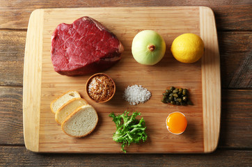 Beef tartare ingredients on wooden cutting board