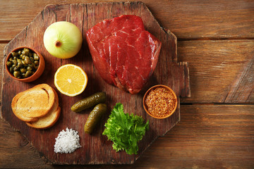 Beef tartare ingredients on wooden cutting board