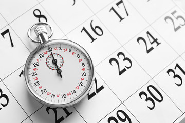 Stopwatch on calendar background, close up