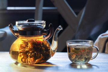 Teapot and glass cup with blooming tea flower inside