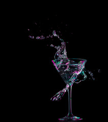 cocktail in glass with splashes on dark background. Party club entertainment. Mixed light.