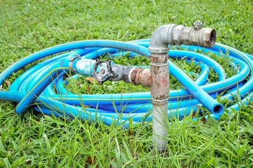 Old water valve with blue rubber water hose in the sunlight