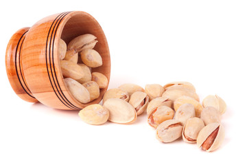 Pistachios pouring out of wooden bowl isolated on white background 