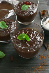 Glass cups of chocolate dessert with fresh mint on black wooden table