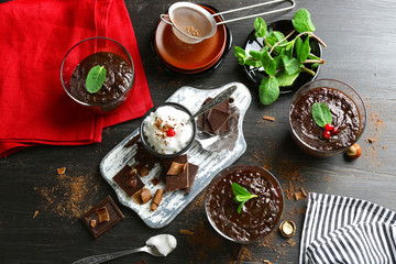 Glass cups of chocolate dessert with fresh mint and frothed milk on black wooden table