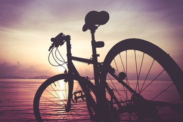Silhouette of bicycle on the beach against colorful sunset in the day time