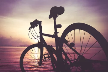 Papier Peint photo Vélo Silhouette of bicycle on the beach against colorful sunset in the day time